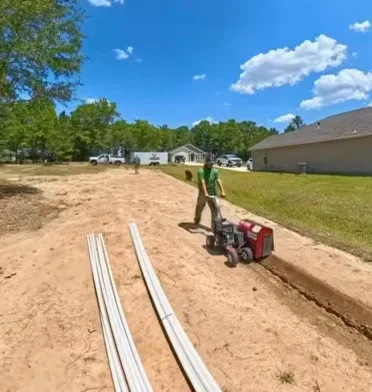 A lawn care professional using machinery on a sandy yard in Panama City, FL, showcasing expert lawn care services for local residents.