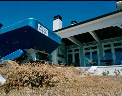 A lawn care professional using a spreader in Panama City, FL, ensuring a lush, healthy lawn for local homeowners.