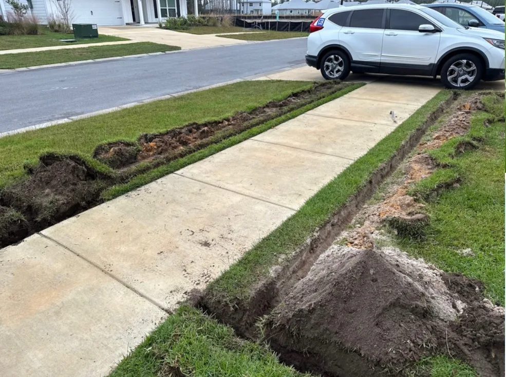 A lawn care service in Panama City, FL, is performing landscaping work, featuring a freshly cut grass edge alongside a sidewalk.